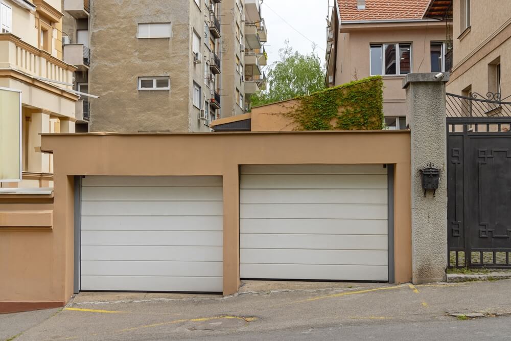 Two-car garage with dark brown doors beneath a steep gray tiled roof 

