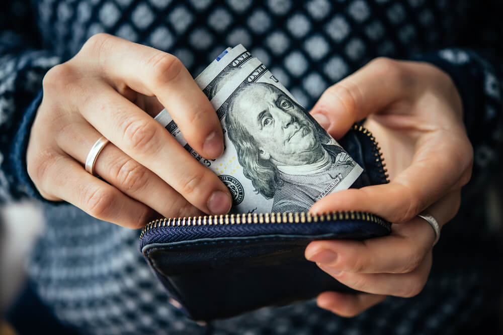 Hands taking out money from inside a wallet