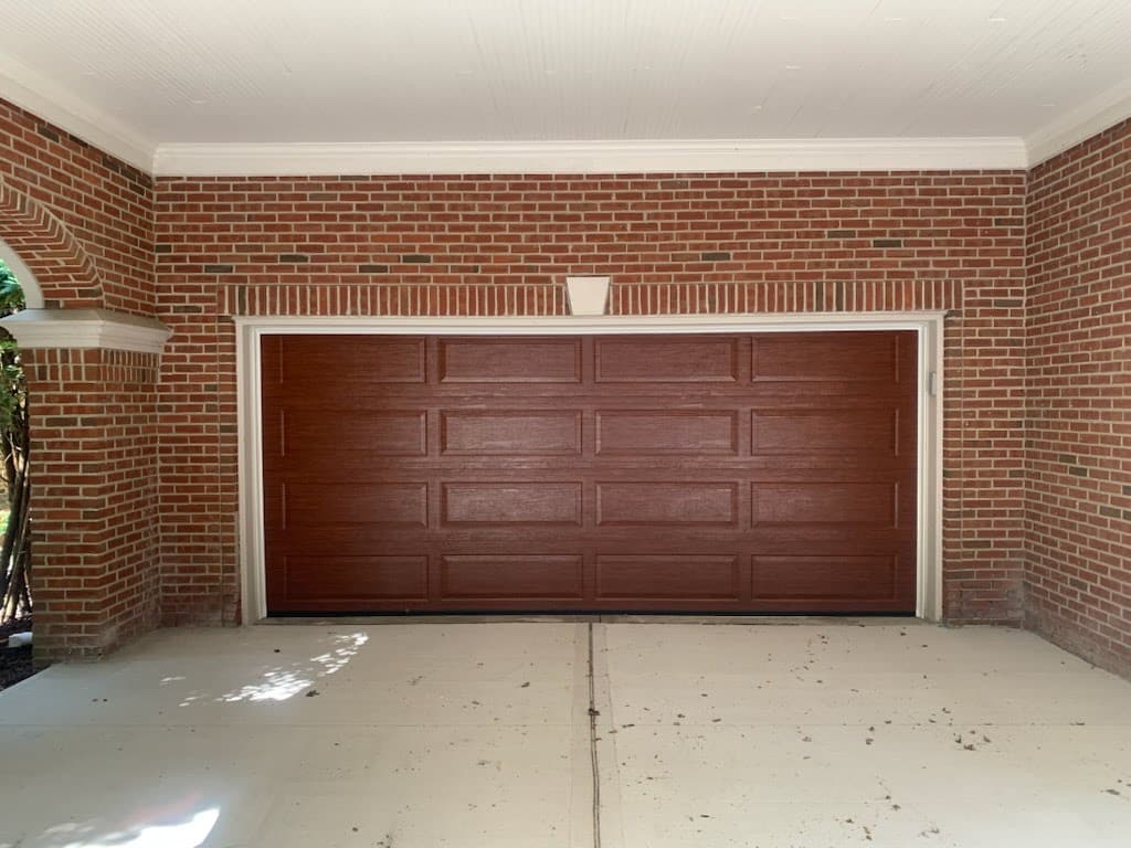 Two-story home with a white garage door, green siding, and a covered front porch