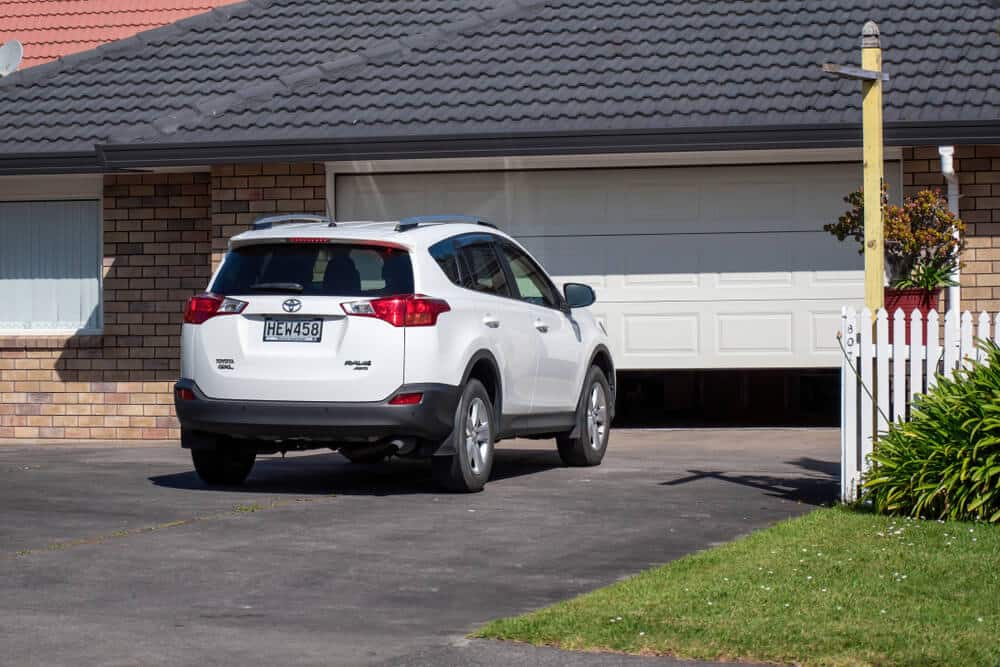 white SUV parked in driveway as residential garage door opens
