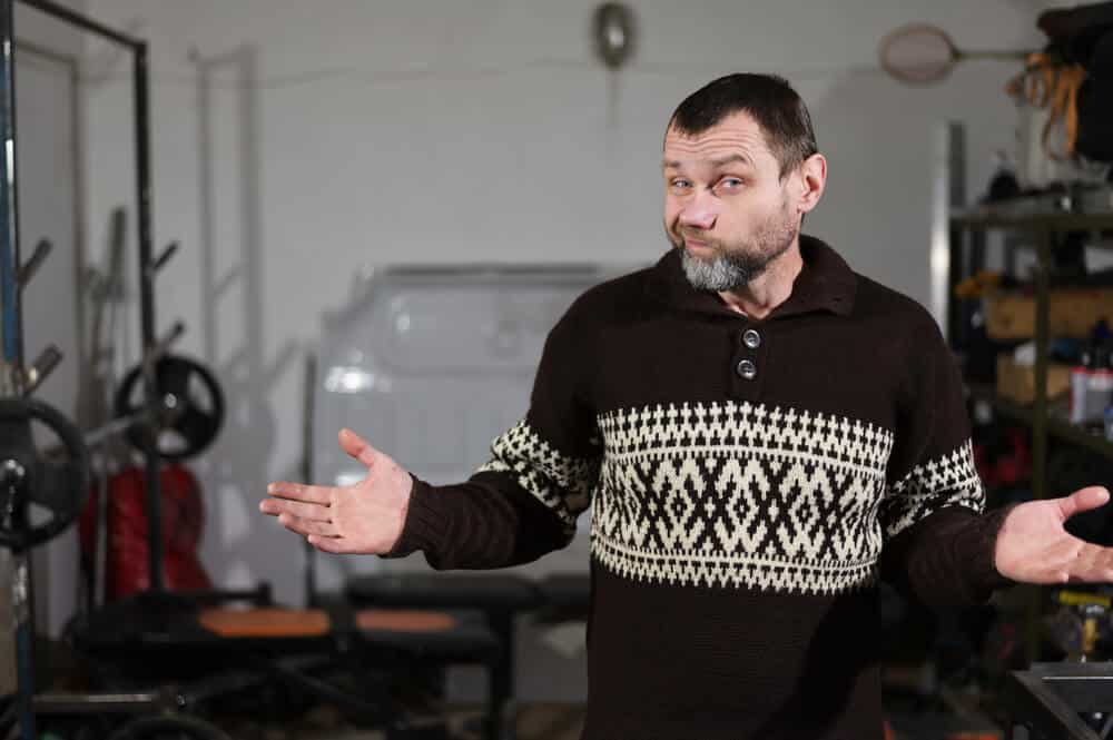 homeowner shrugging inside garage with confused expression