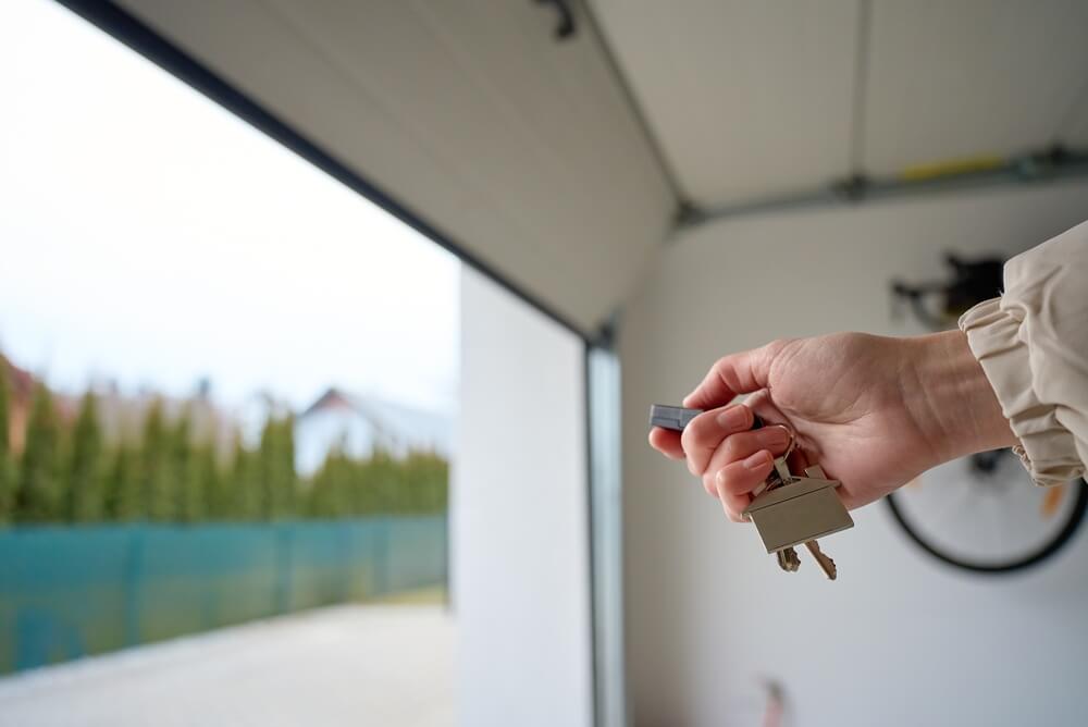 hand holding garage door remote and keys inside open garage